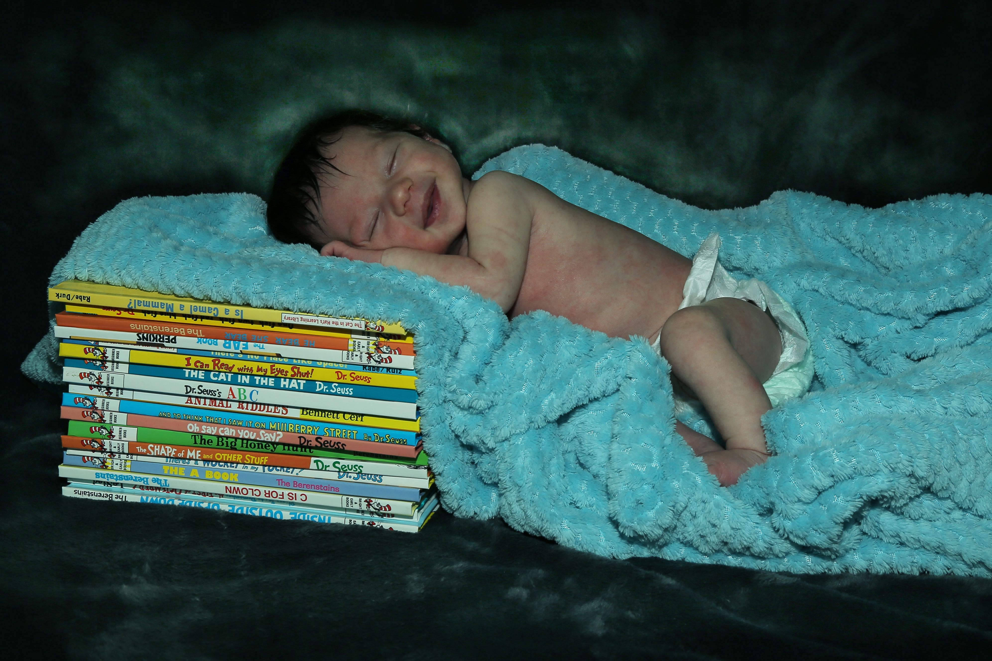 baby on a blanket laying on books
