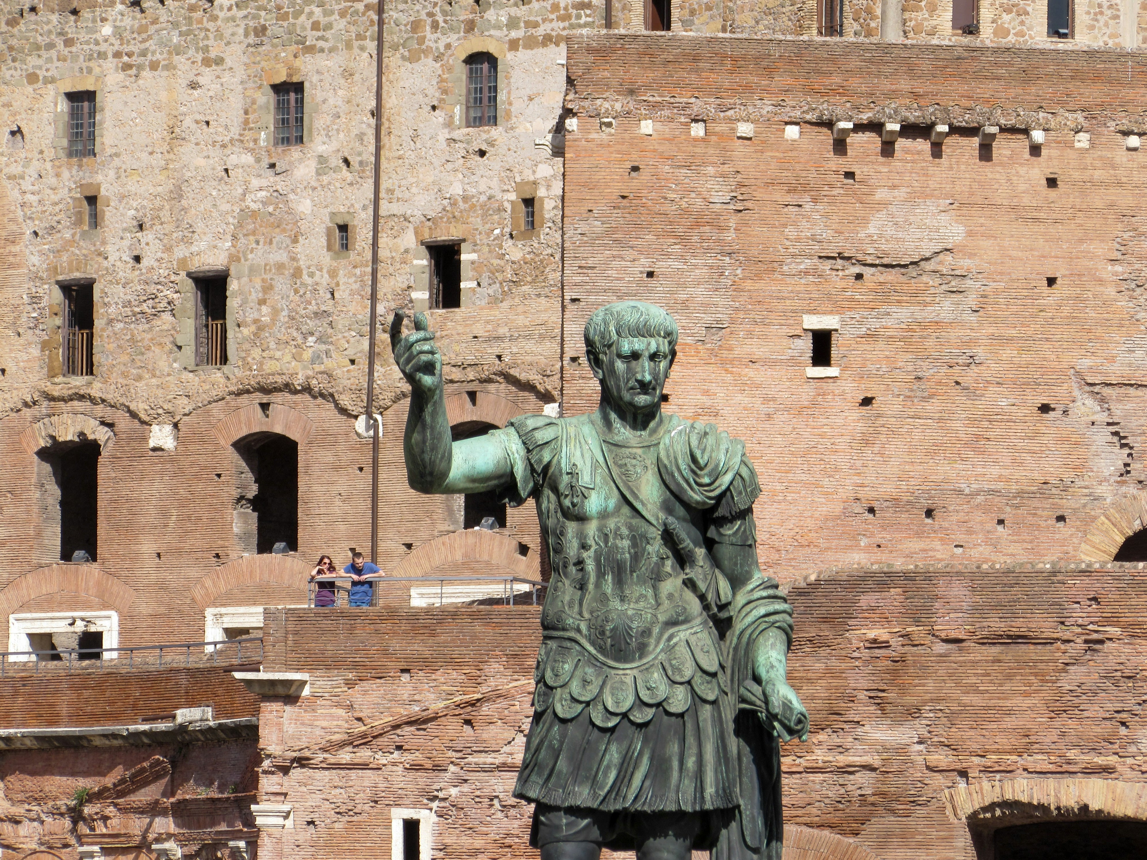 A statue of a roman soldier in front of a castle